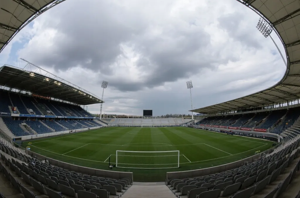 A wide view of a modern soccer stadium under a dramatic sky